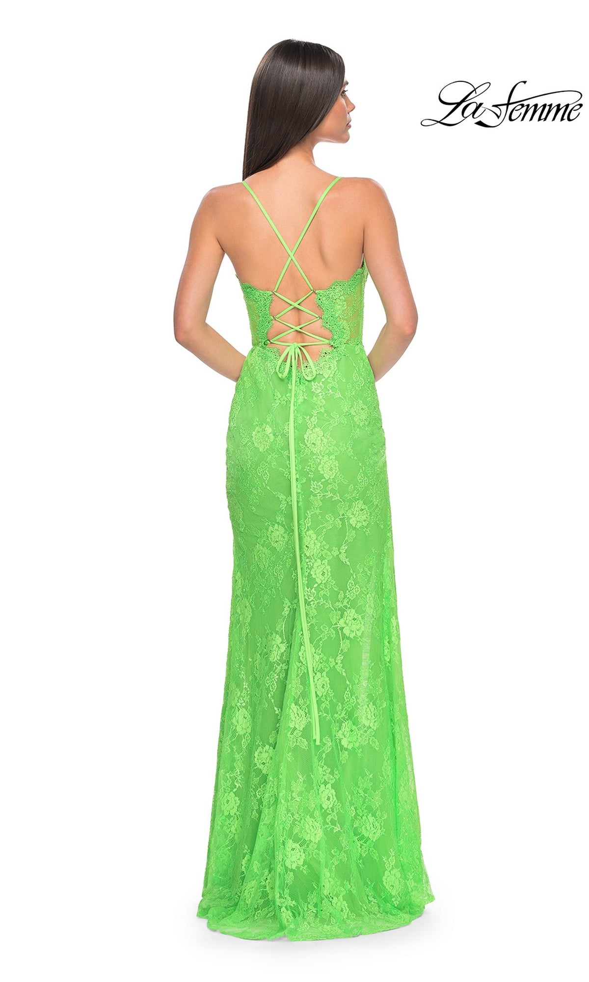 A woman stands facing away in the La Femme Bright Long Lace Prom Dress 32441, featuring neon green lace and a crisscross lace-up back. The